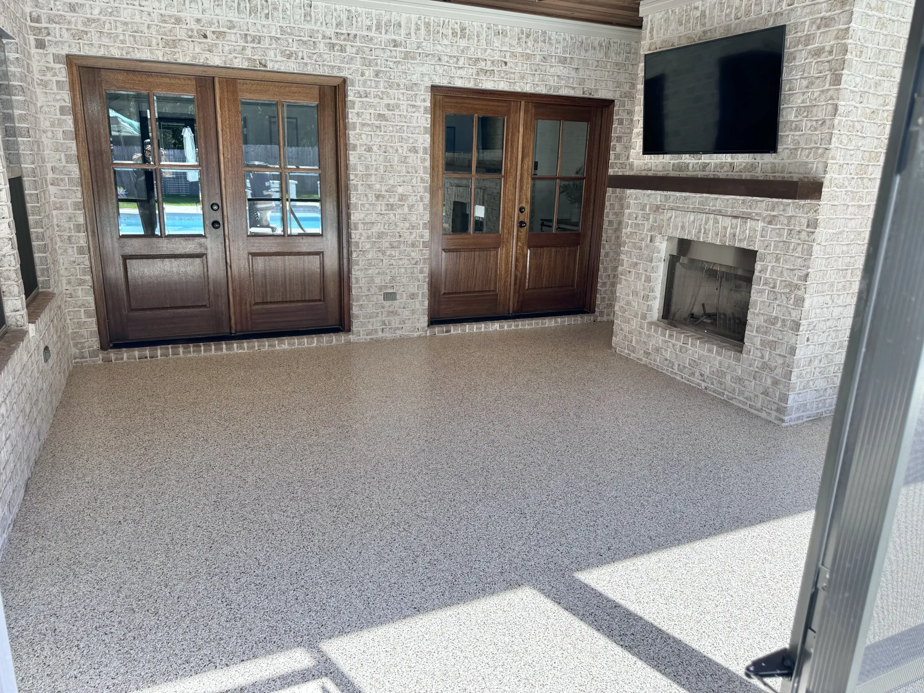 Finished covered porch with a fireplace and French doors